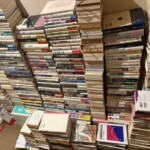神戸市灘区で遺品整理の出張買取をした蔵書。物理学や宇宙、数学、経済学の本が床に高く積まれた様子