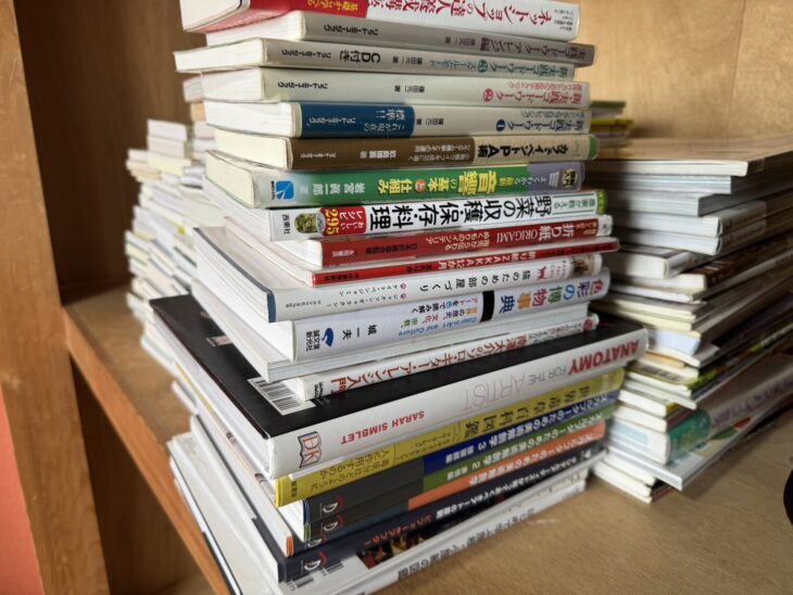 神戸市で出張買取したイラスト・デザイン・美術の本。サラ・シンブレット『芸術家のための人体解剖図鑑』やデザイン・色彩の本が積まれた様子
