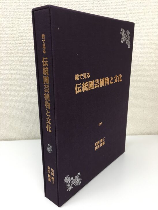 紫紺の布装の函と本体が並び、絵で見る伝統園芸植物と文化の題字と菊の意匠が金で箔押しされている