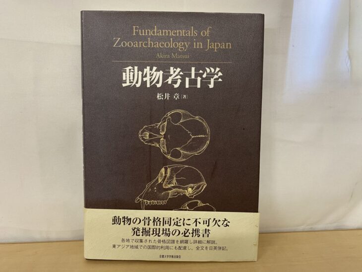 動物考古学の焦げ茶の表紙に頭骨の図とFundamentals of Zooarchaeology in Japanの英題が金で刷られ、帯に発掘現場の必携書とある