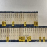 講談社『現代囲碁大系』全48冊の函が2段に並び、配本の帯が残る様子