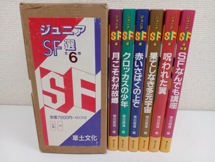 ジュニアSF選の赤と青の外箱と、紫や緑など色の違う6冊の背が並び、月こそわが故郷やSFなんでも講座の書名が入っている
