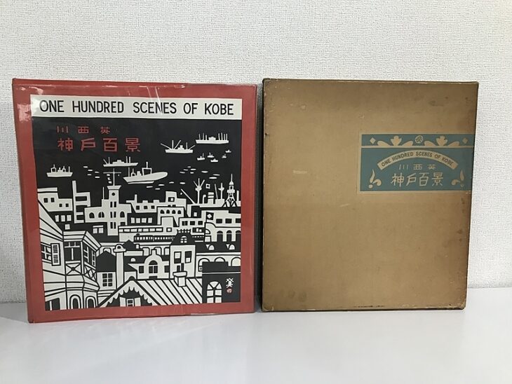 川西英『神戸百景』の表紙に黒地で刷られた神戸の港と洋館、隣に水色の題簽を貼った茶色の外函