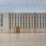 丸山眞男集の生成りの函が17冊並び、背に巻番号と1936から1988までの収録年、第四巻と第五巻に配本の帯が付いている