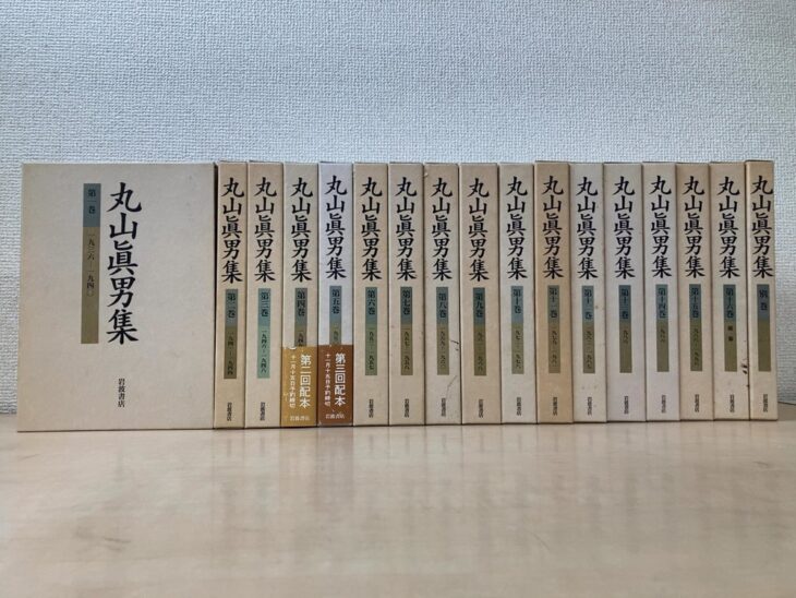 丸山眞男集の生成りの函が17冊並び、背に巻番号と1936から1988までの収録年、第四巻と第五巻に配本の帯が付いている