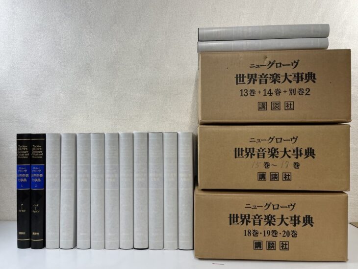 ニューグローヴ世界音楽大事典の黒い函2冊と灰色の本体が並び、右に13巻から20巻が入った講談社の輸送用ダンボール3箱が積まれている
