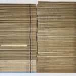 日本名跡叢刊の生成りの冊子が上下二列に約50冊ずつ積まれ、背に巻番号と各巻の作品名が入っている