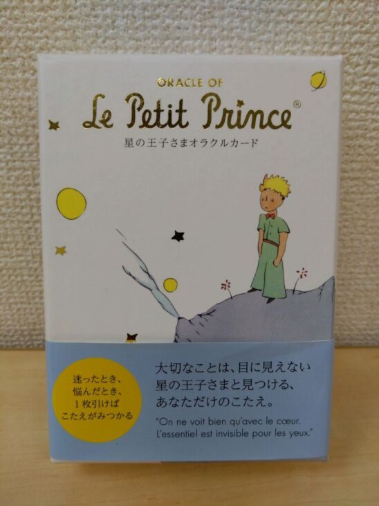 星の王子さまオラクルカードの白い箱。Le Petit Princeの金の箔押しと、星の上に立つ王子の絵が入り、下に水色の帯が掛かっている