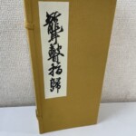 聾瞽指帰の複製本が黄土色の布貼りの帙に収まり、白地の題簽に草書の題字が入る