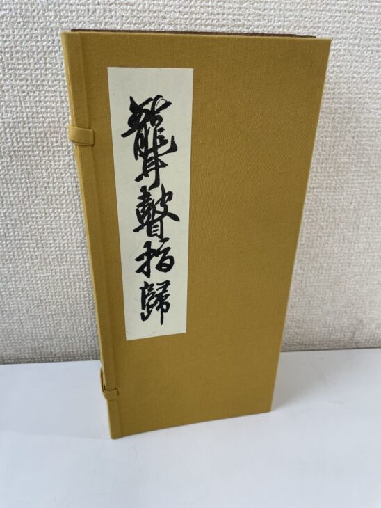 聾瞽指帰の複製本が黄土色の布貼りの帙に収まり、白地の題簽に草書の題字が入る
