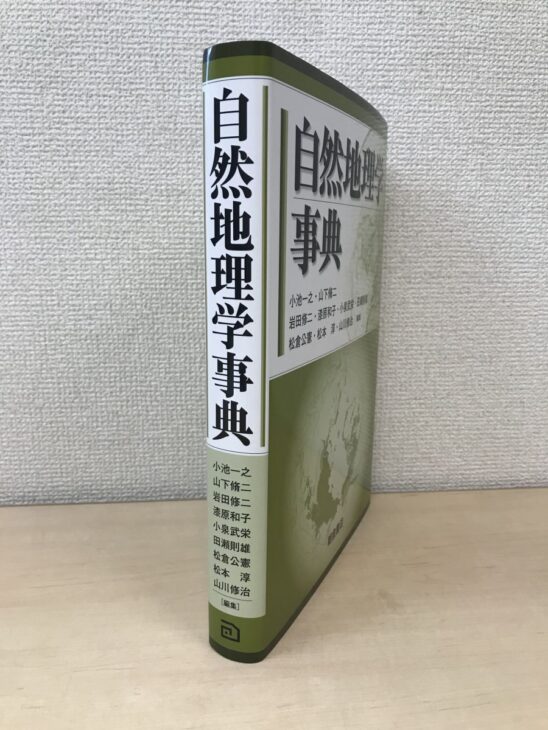 自然地理学事典の白い背に小池一之から山川修治まで9人の編集者名が並び、カバーに地球の地図があしらわれている