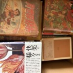 手塚治虫『魔法屋敷』と『月世界探検』の色刷りカバー、その下に『快楽の様々』の帯が見える段ボール