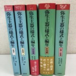弥生土器の様式と編年の近畿編から山陽・山陰編まで5冊が並び、赤い背の上部に鹿や仮面の絵画土器の意匠が白く抜かれている