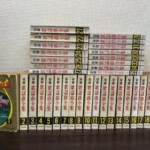 全音歌謡曲全集の1巻から35巻が背表紙の巻数順に三段へ並び、1巻だけ表紙の洋蘭が見える