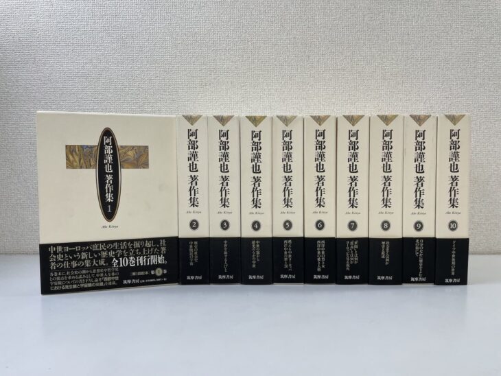 筑摩書房『阿部謹也著作集』のクリーム色の函10個。左端に第1巻の函の正面と黒い帯、右に第2巻から第10巻の函の背が並ぶ