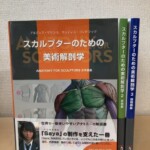 スカルプターのための美術解剖学の1巻を手前に置き、緑の背の2 表情編と青の背の3 頭頸部編を立てた3冊。1巻にはSayaの帯がついている