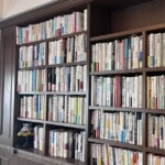 濃い茶色の造り付けの本棚にびっしりと本が入り、棚のひとつに色ガラスのランプが置かれた大阪市旭区の部屋