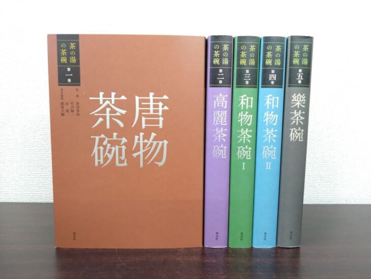 赤茶色の第一巻『唐物茶碗』を正面に向け、薄紫、緑、水色、灰色の背の第二巻から第五巻を並べた淡交社『茶の湯の茶碗』