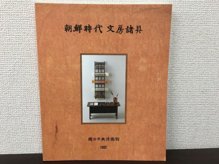 國立中央博物館『朝鮮時代 文房諸具』の柿色の表紙と、縦長の木の棚や低い机、筆筒の写真