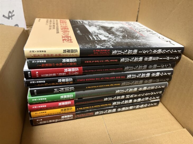 広田厚司『ドイツV号戦車パンター戦場写真集』『ティーガーI&II戦車戦場写真集』『ロンメルとアフリカ軍団戦場写真集』など帯付きの戦場写真集9冊が段ボールに重なる