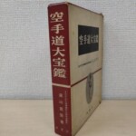 赤い背に白い字で空手道大宝鑑、遠山寛賢著、鶴書房と入った函。正面には黒い長方形に白い字の書名と、楕円に入った道着姿の人の写真