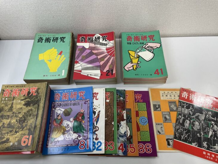 緑や赤の表紙が並ぶ季刊『奇術研究』創刊号から第86号と、黄色の分類総目録、赤い臨時増刊の88冊