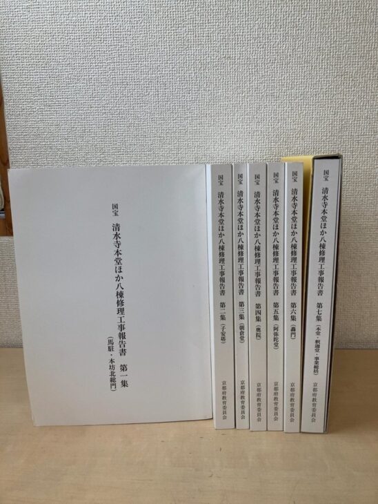 国宝 清水寺本堂ほか八棟修理工事報告書の第二集から第七集を立てて並べ、第一集の表紙(馬駐・本坊北総門)を手前に置いた京都府教育委員会の7冊