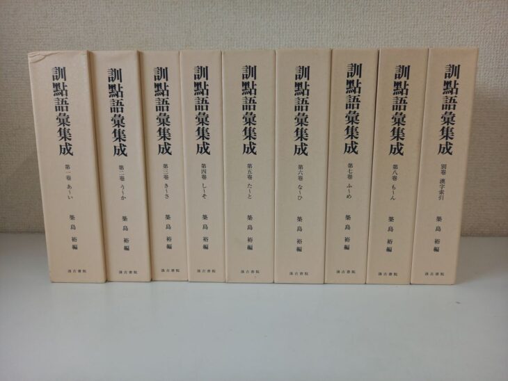 汲古書院『訓點語彙集成』のクリーム色の函9つ。背に旧字の大きな書名と、第一巻 あ〜いから第八巻 も〜ん、別巻 漢字索引の巻数、築島裕 編と汲古書院の文字が並ぶ