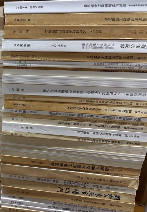 厳島神社や東照宮、各地の住宅の修理工事報告書を、背が見えるように積んだ山