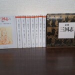 ちくま学芸文庫『正史 三国志』8冊と外箱。左端の第1巻は表紙に朱色の線の人物画と「魏書I」、第2巻から第8巻は背に巻数と訳者名、右に黒と茶色で馬や人を描いた箱