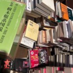 緑の函に入った苅住曻『最新 樹木根系図説』と、床に積んだ新書、投資の本、京都の老舗のムック