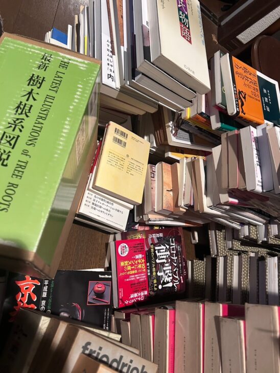 緑の函に入った苅住曻『最新 樹木根系図説』と、床に積んだ新書、投資の本、京都の老舗のムック