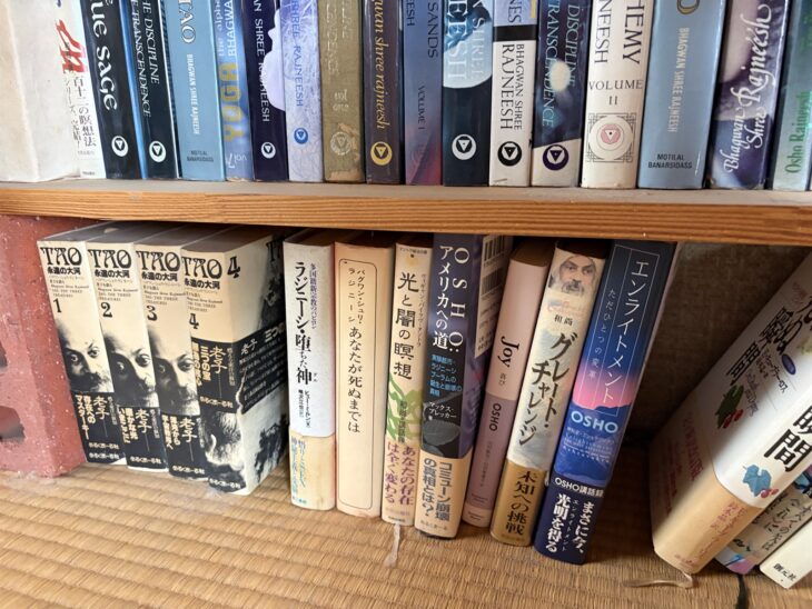 めるくまーる社『TAO 永遠の大河』1から4と、ヒュー・ミルン『ラジニーシ・堕ちた神』、OSHO『エンライトメント』が並ぶ棚の下段