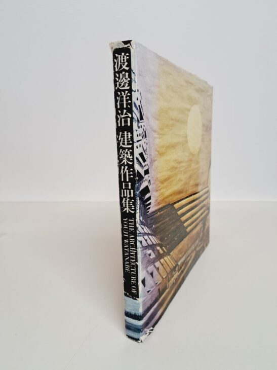 カバーの背に「渡邊洋治 建築作品集」と英字の書名が入った正方形の作品集。表には建物の壁と丸い光の写真