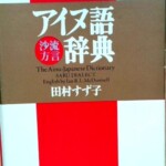草風館『アイヌ語沙流方言辞典』の表紙。赤と白の地に茶色の帯状の枠があり、白い字の書名と「沙流方言」、英語の題、田村すず子の名前