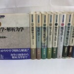 岩波書店『岩波基礎物理シリーズ』10冊。左の第1巻は表紙に丸で囲んだ1と「力学・解析力学」、下に青紫の帯。右の9冊は背に巻数と書名、第7巻を除く8冊は下の帯に著者名