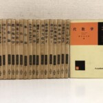 黒い布装の基礎数学講座が20冊並び、背に金の字で位相数学 近代解析 函数論 微分幾何学 整数論 集合論などの題と番号。右に第1巻 代数学の表紙