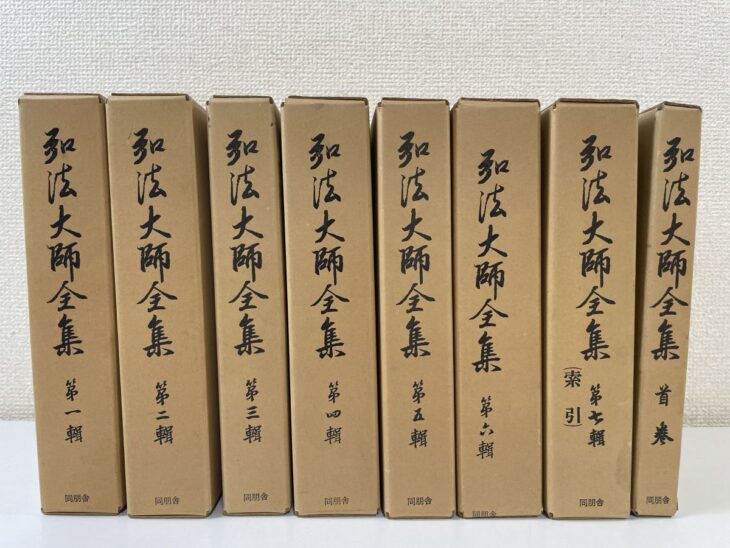 筆書きの書体で弘法大師全集と入った段ボール地の函8つ。背に第一輯から第七輯と首巻、下に同朋舎の文字