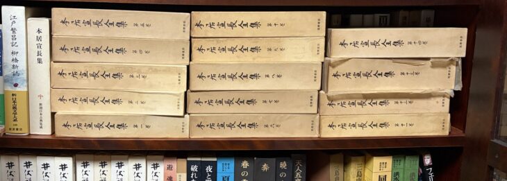 筑摩書房『本居宣長全集』第1巻から第14巻の函が3列に積まれ、左に新潮日本古典集成『本居宣長集』と岩波書店『江戸繁昌記 柳橋新誌』