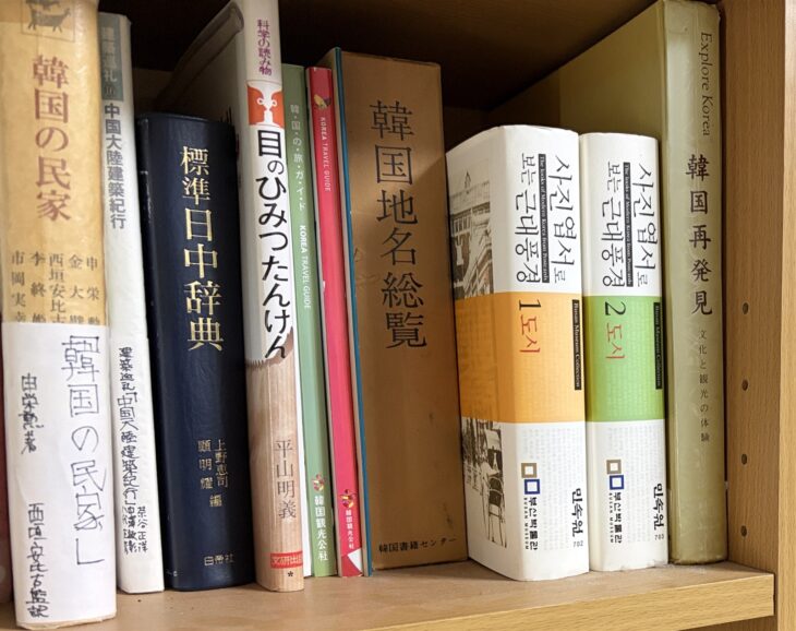 申栄勲『韓国の民家』、茶谷正洋『中国大陸建築紀行』、上野恵司・顧明耀編『標準日中辞典』、『韓国地名総覧』が並ぶ本棚の一段