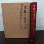 黒い枠に書名を入れた茶色い紙の函と、えんじ色の布の背に金文字で修験道修行大系と入った本体1冊