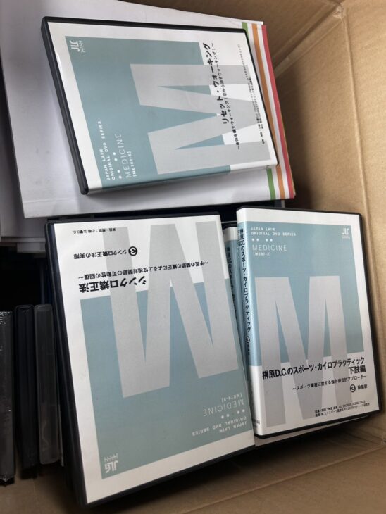 段ボール箱に入ったジャパンライムのDVD。榊原D.C.のスポーツ・カイロプラクティック 下肢編 股関節、シンクロ矯正法、リセット・ウォーキング