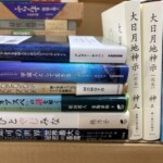 段ボールに詰めた精神世界の本。左に『宇宙意識で生きる地球人のためのスピリチュアルガイド』『宇宙人として生きる』『よひとやむみな』の背、右に神人『大日月地神示』前巻と後巻