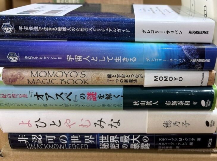 横に積んだ6冊の背。グレゴリー・サリバン『宇宙意識で生きる地球人のためのスピリチュアルガイド』『宇宙人として生きる』、『MOMOYO'S MAGIC BOOK』、『「オアスペ」の謎を解く』、穂乃子『よひとやむみな』、『非認可の世界』