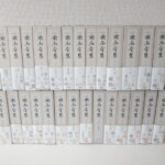 定本漱石全集の白い函29冊が2段に並び、背に定本の文字と漱石全集の題、帯に笑う日常 幻想と漱石 情熱の塊などの文句