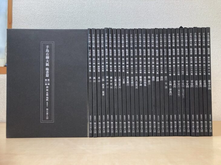 独立書人団『手島右卿大観』臨書篇30巻。左に大きな黒い函、右に黒い背の本30冊。背に巻数と漢、蘭亭序、王羲之之書、唐、平安などの巻名