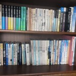 木の本棚2段。『解析入門』『線型代数入門』の基礎数学シリーズ、『フィードバック制御入門』『伝熱工学』、グライナー『量子力学概論』、『自動車力学』『タイヤ工学』『自動車技術ハンドブック』